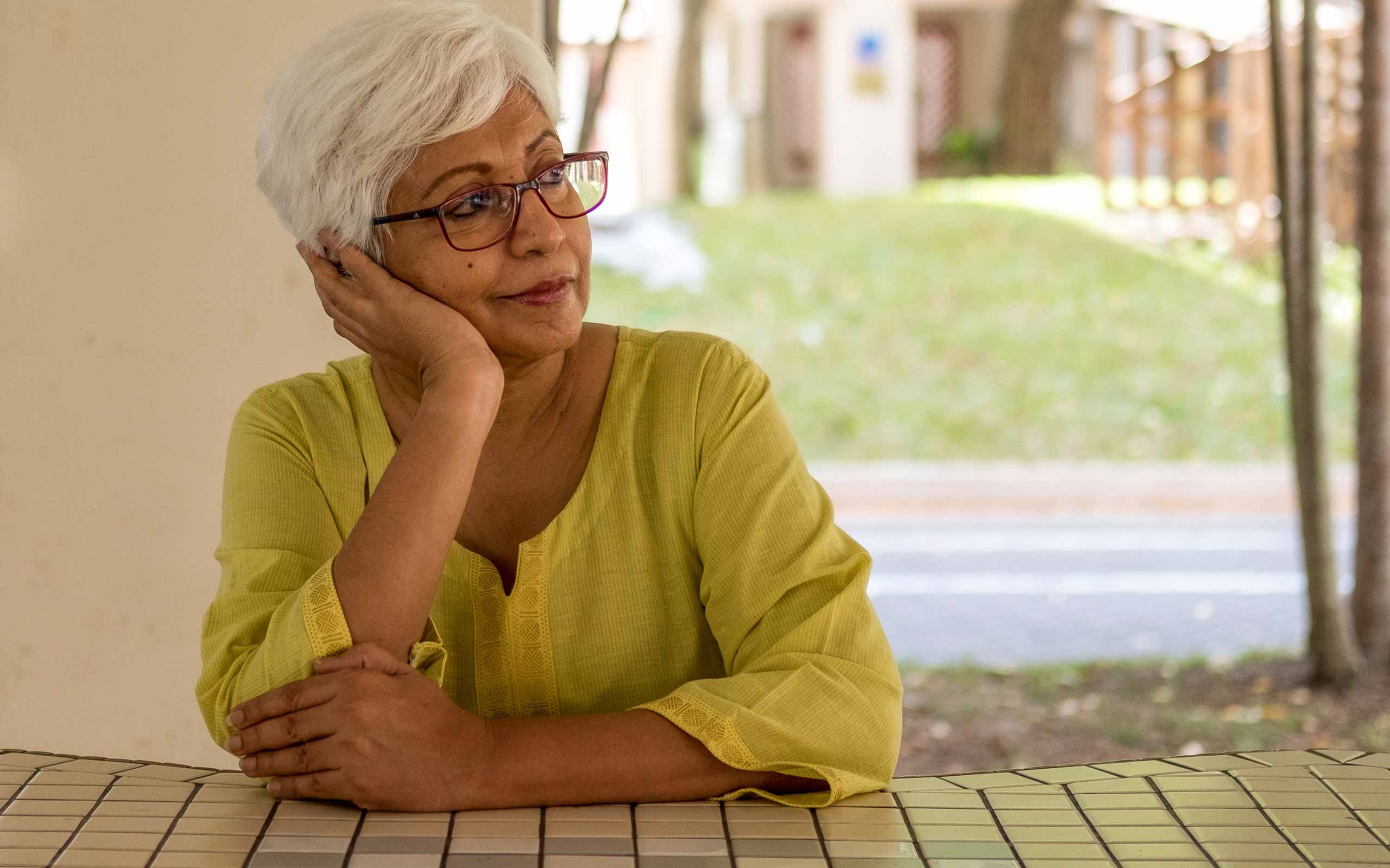 An older, white-haired woman sitting and looking off to the side