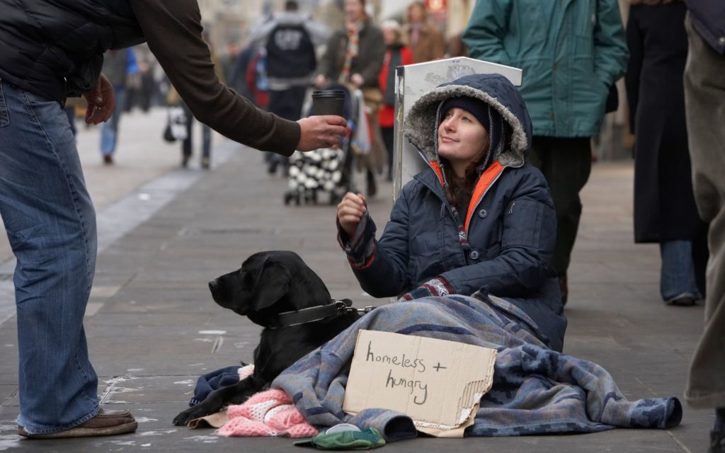 A homeless woman sitting on the sidewalk