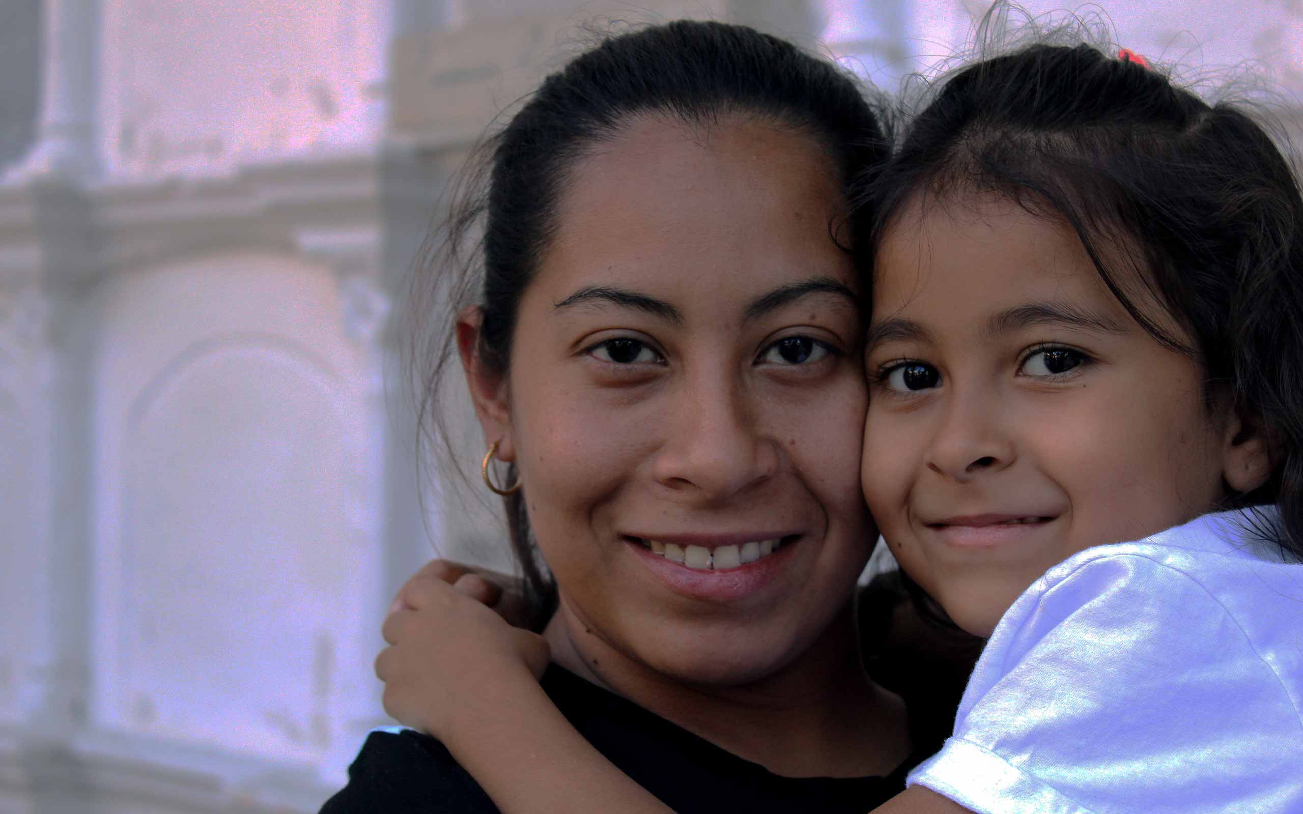 A mother holding her daughter and smiling