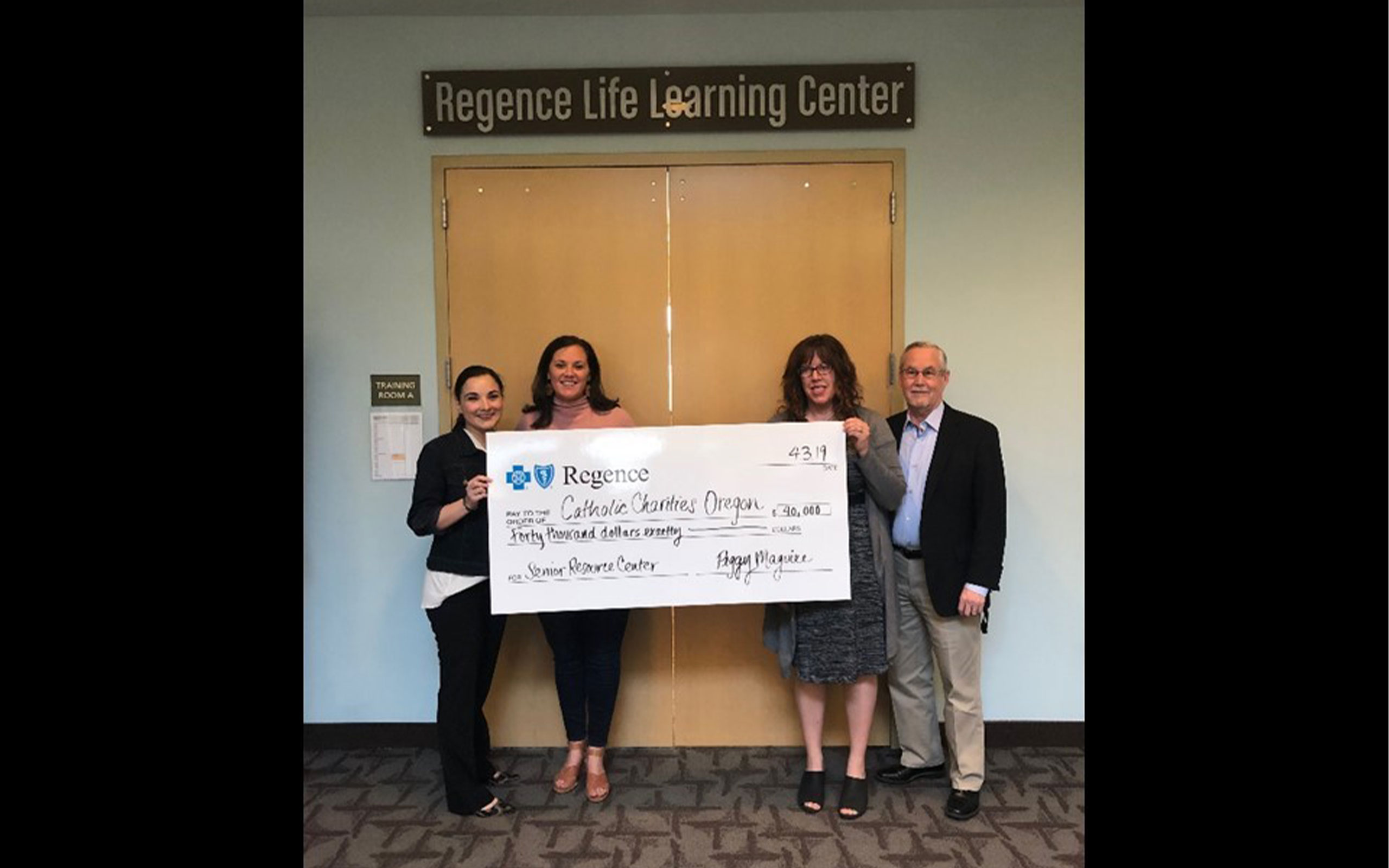 Catholic Charities staff holds up a check for $40,000 from Regence, representing another year of partnership