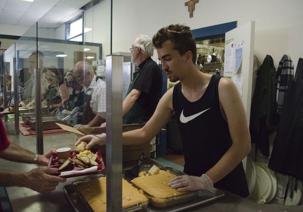A volunteer serves food at the St. Francis Dining Hall