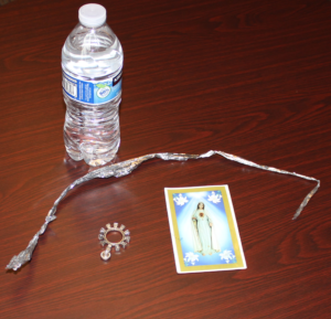 A water bottle, rosary, prayer card, and strip of mylar, all commonly found at respite centers